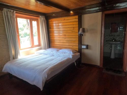 a bedroom with a bed with a window and a sink at Dhampus Village Eco Lodge in Kāskī