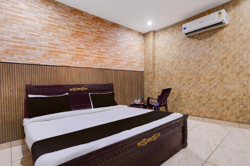 a bedroom with a large bed and a chair at Hotel O Faridabad Central Railway Junction Formerly Diamond in Faridabad
