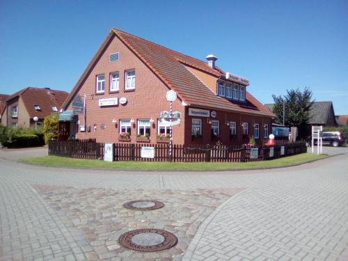 a building with a fence in front of a street at Gästehaus Restaurant Norddeich in Norddeich