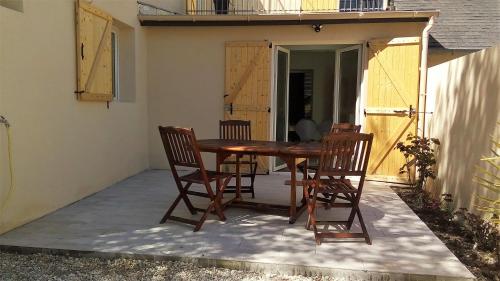 une table et des chaises en bois sur une terrasse dans l'établissement Les Muguets, à Villers-sur-Mer