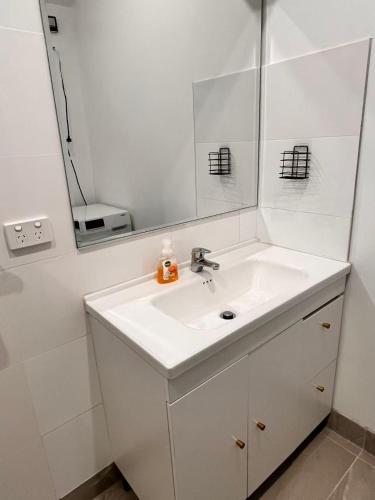 a white bathroom with a sink and a mirror at Bright & Quiet 1BR with Courtyard in Williams Landing