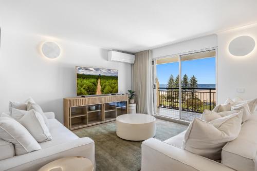 a living room with white furniture and a view of the ocean at Oceanfront 3-Bed Retreat with Pool-Steps to Beach in Caloundra