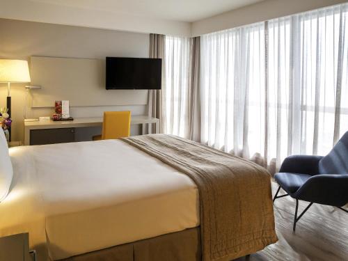 a hotel room with a bed and a chair at Novotel Florianopolis in Florianópolis