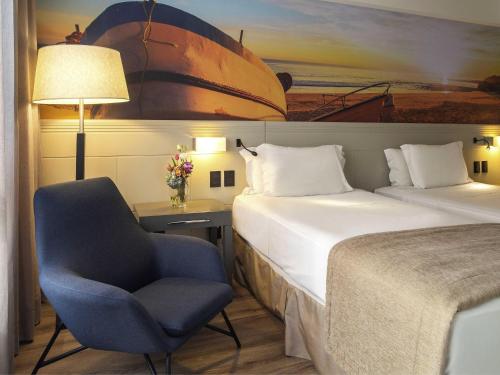 a hotel room with a bed and a chair at Novotel Florianopolis in Florianópolis