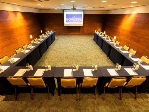 a conference room with tables and chairs in front of a screen at Novotel Florianopolis in Florianópolis