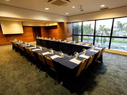 a conference room with a long table and chairs at Novotel Florianopolis in Florianópolis