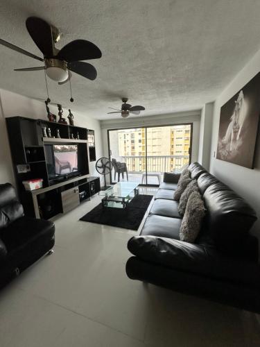 a living room with a black leather couch and a television at Apartamento frente al MAR Rodadero - Gaira TACOA 6 a 8 personas in Rodadero