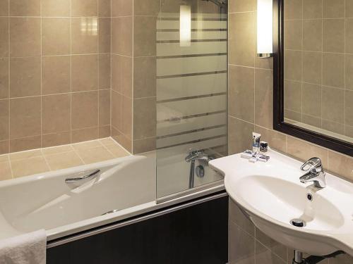 a bathroom with a sink and a bath tub at Hotel Mercure Rennes Cesson in Cesson-Sévigné