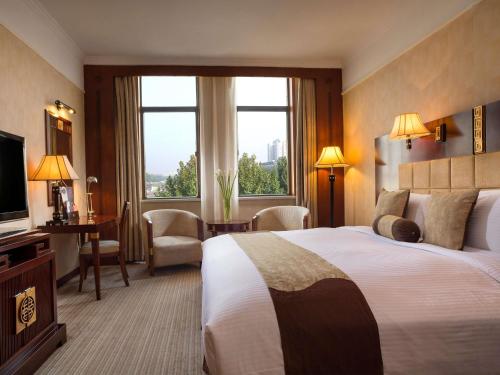 a hotel room with a bed and a large window at Grand Mercure Xian On Renmin Square in Xi'an
