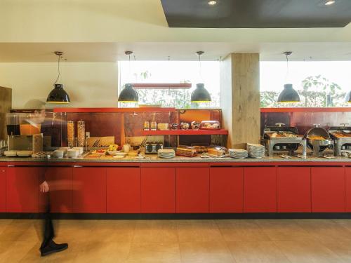 a kitchen with red cabinets and a counter with food at Ibis Mexico Perinorte in Mexico City