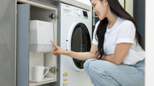 a woman sitting in front of a washing machine at Centum Mark Kimstay Yangyang in Yangyang