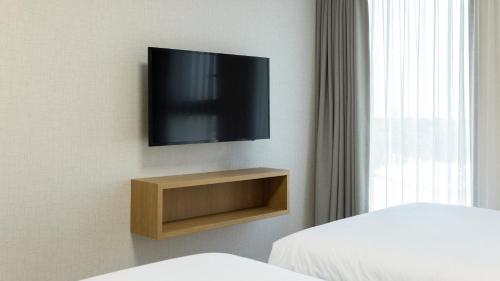 a room with a television on a wall with two beds at Centum Mark Kimstay Yangyang in Yangyang