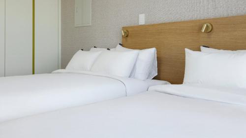 two beds in a hotel room with white pillows at Centum Mark Kimstay Yangyang in Yangyang