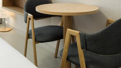 a wooden table with two chairs and a small table at Centum Mark Kimstay Yangyang in Yangyang