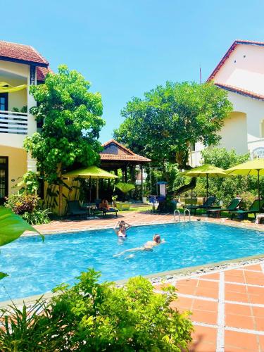 two people in a swimming pool at a hotel at The Muse House in Hoi An