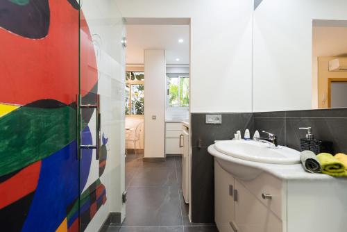 a bathroom with a sink and a colorful painting on the wall at Suites Garden Loft Miro in Las Palmas de Gran Canaria