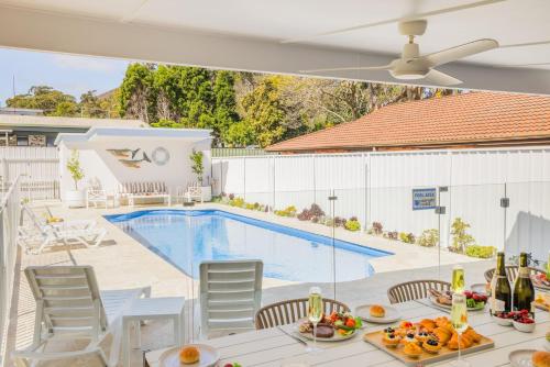 a patio with a pool and a table with food on it at Shoal Shack 72, 72 Tomaree Rd - Pool, Pet Friendly, Wi-Fi, Air Con, Linen in Shoal Bay