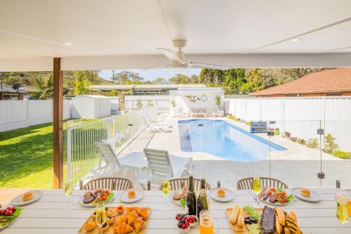 a table with food on it next to a swimming pool at Shoal Shack 72, 72 Tomaree Rd - Pool, Pet Friendly, Wi-Fi, Air Con, Linen in Shoal Bay
