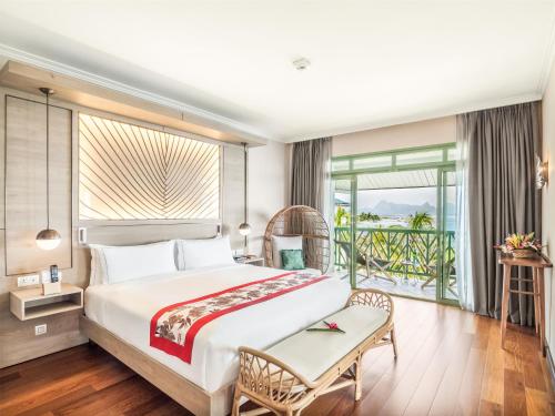 a bedroom with a large bed and a balcony at Hilton Hotel Tahiti in Papeete