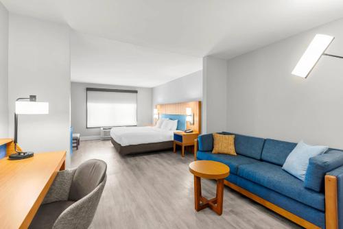 a living room with a blue couch and a bed at Country Inn & Suites Etown in Elizabethtown