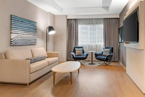 a living room with a couch and chairs and a tv at Radisson Plaza Hotel at Kalamazoo Center in Kalamazoo