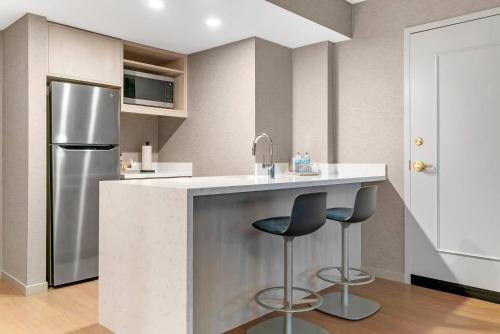 a kitchen with a refrigerator and two bar stools at Radisson Plaza Hotel at Kalamazoo Center in Kalamazoo