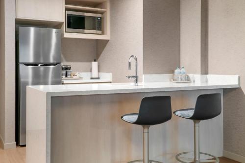 a kitchen with two bar stools and a refrigerator at Radisson Plaza Hotel at Kalamazoo Center in Kalamazoo