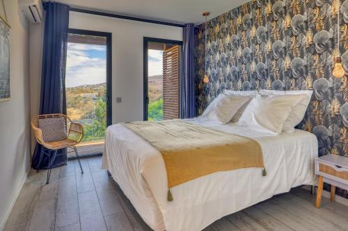 a bedroom with a bed and a large window at Le Moma by the ocean in Trois Bassins