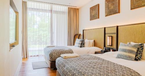 a hotel room with two beds and a window at UMITO Okinawa Onnason in Onna