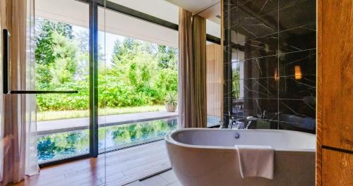 a bathroom with a tub and a large window at UMITO Okinawa Onnason in Onna