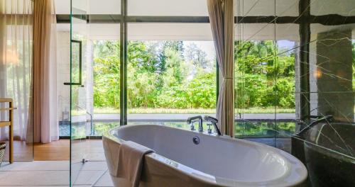 a bath tub in a bathroom with a large window at UMITO Okinawa Onnason in Onna