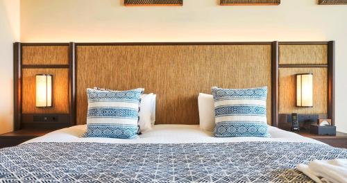 a bedroom with a large bed with blue and white pillows at UMITO Okinawa Onnason in Onna