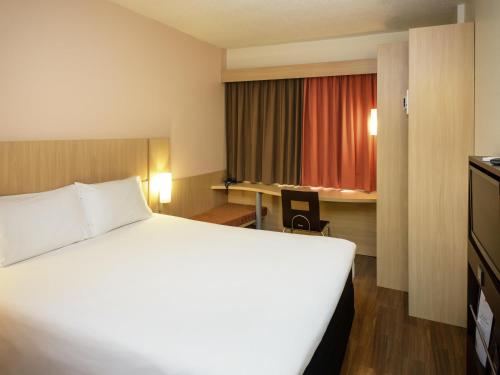 a hotel room with a large white bed and a desk at ibis Recife Boa Viagem in Recife