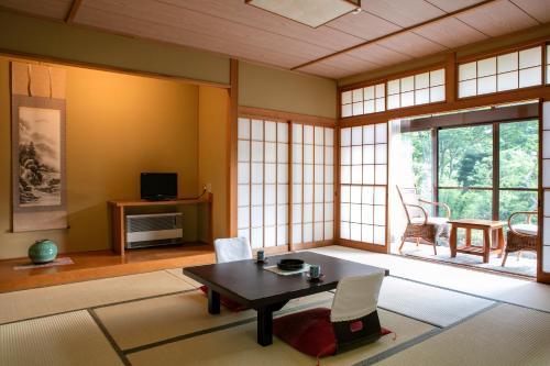 un soggiorno con tavolo, sedie e finestre di Ryokan Warabino a Takayama