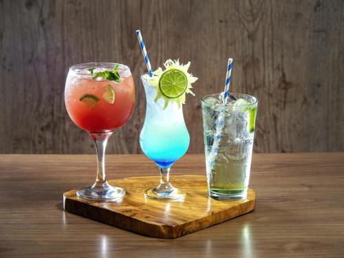 three cocktails sitting on a wooden tray on a table at ibis Recife Boa Viagem in Recife