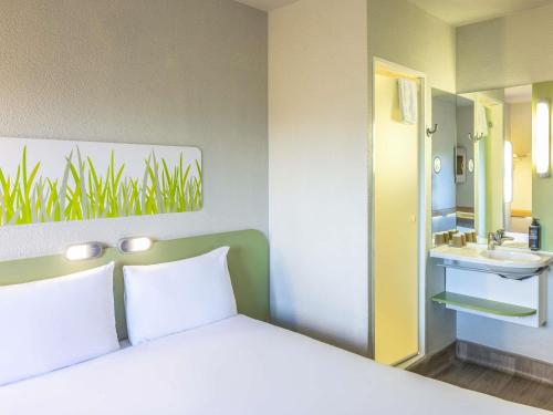 a bedroom with a bed and a sink and a mirror at ibis budget Manchester Salford Quays in Manchester