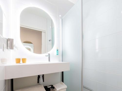 a white bathroom with a sink and a mirror at Novotel Suites Montpellier Antigone in Montpellier