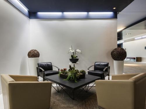 a waiting room with chairs and a table with plants at Novotel Montréal Aéroport in Dorval