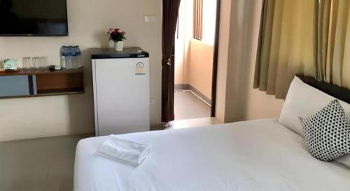 a bedroom with a white bed and a small refrigerator at Regent Room Hotel in Suratthani