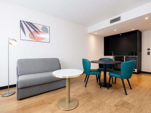 a living room with a couch and a table and chairs at Novotel Suites Montpellier Antigone in Montpellier