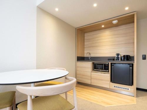 a kitchen with a white table and a microwave at Novotel Suites Montpellier Antigone in Montpellier