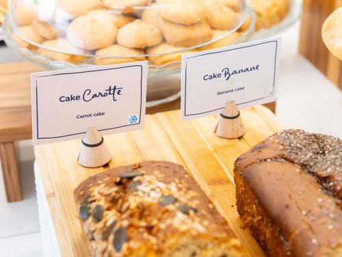 a loaf of bread on a cutting board with three signs at Novotel Suites Montpellier Antigone in Montpellier