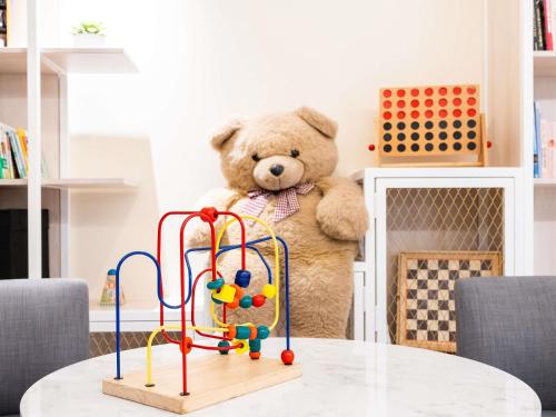 a teddy bear standing next to a toy on a table at Novotel Suites Montpellier Antigone in Montpellier