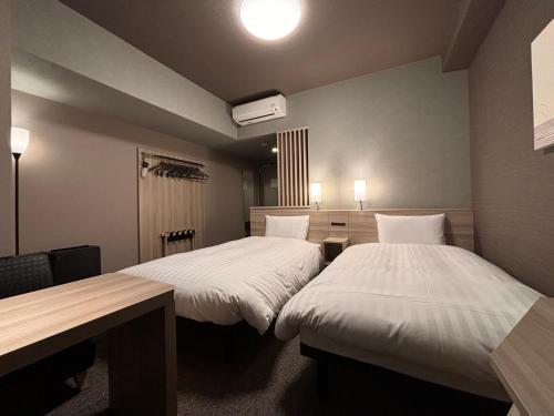 a room with two beds and a desk in it at Hotel Route Inn Kyoto Kumiyama in Kyoto