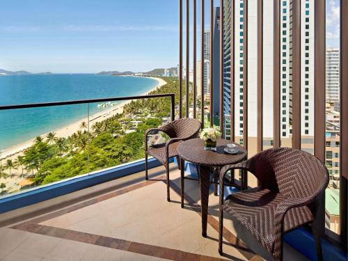 a balcony with two tables and chairs and a beach at Novotel Nha Trang in Nha Trang