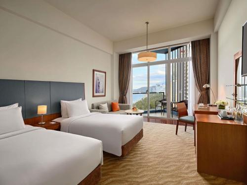 a hotel room with two beds and a desk at Novotel Nha Trang in Nha Trang