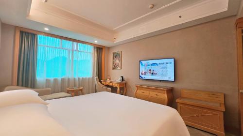 a bedroom with a large bed and a flat screen tv at Vienna Hotel Jishou Qianzhou Ancient City Branch 