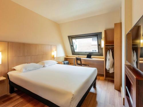 a hotel room with a large white bed and a window at Ibis Bilbao Centro in Bilbao