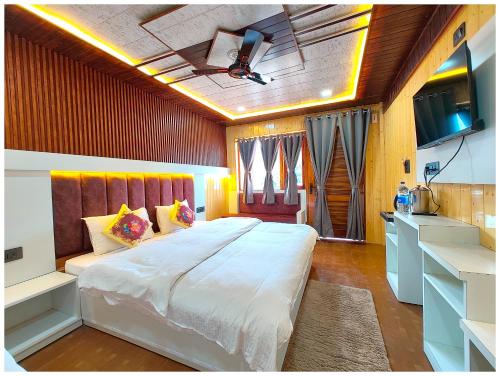 a bedroom with a large white bed and a tv at HOTEL BOUTIQUE SANGITA PARADISE LAKE VIEW MALL ROAD NAINITAL - Newly Decorated - Near Mall Road Laxurious Lake View Rooms With Balcony - Free Parking & Wi-fi - Restaurant Facilities - Best Hotel In Nainital in Nainital