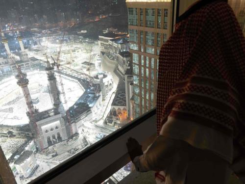 a person looking out of a window at a city at Pullman ZamZam Makkah in Makkah